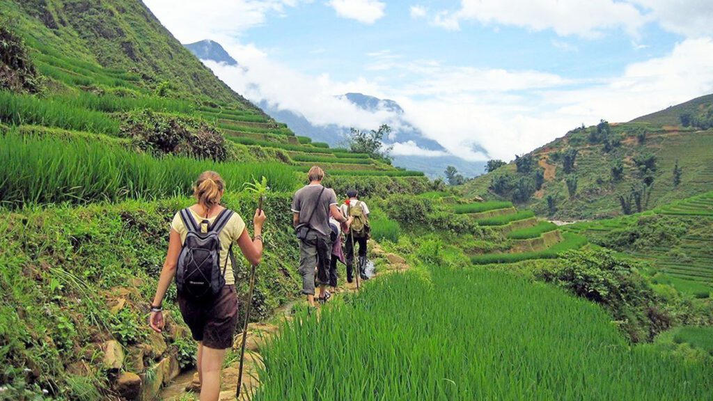 Travelers walking along a mountain trail through green terraced rice fields